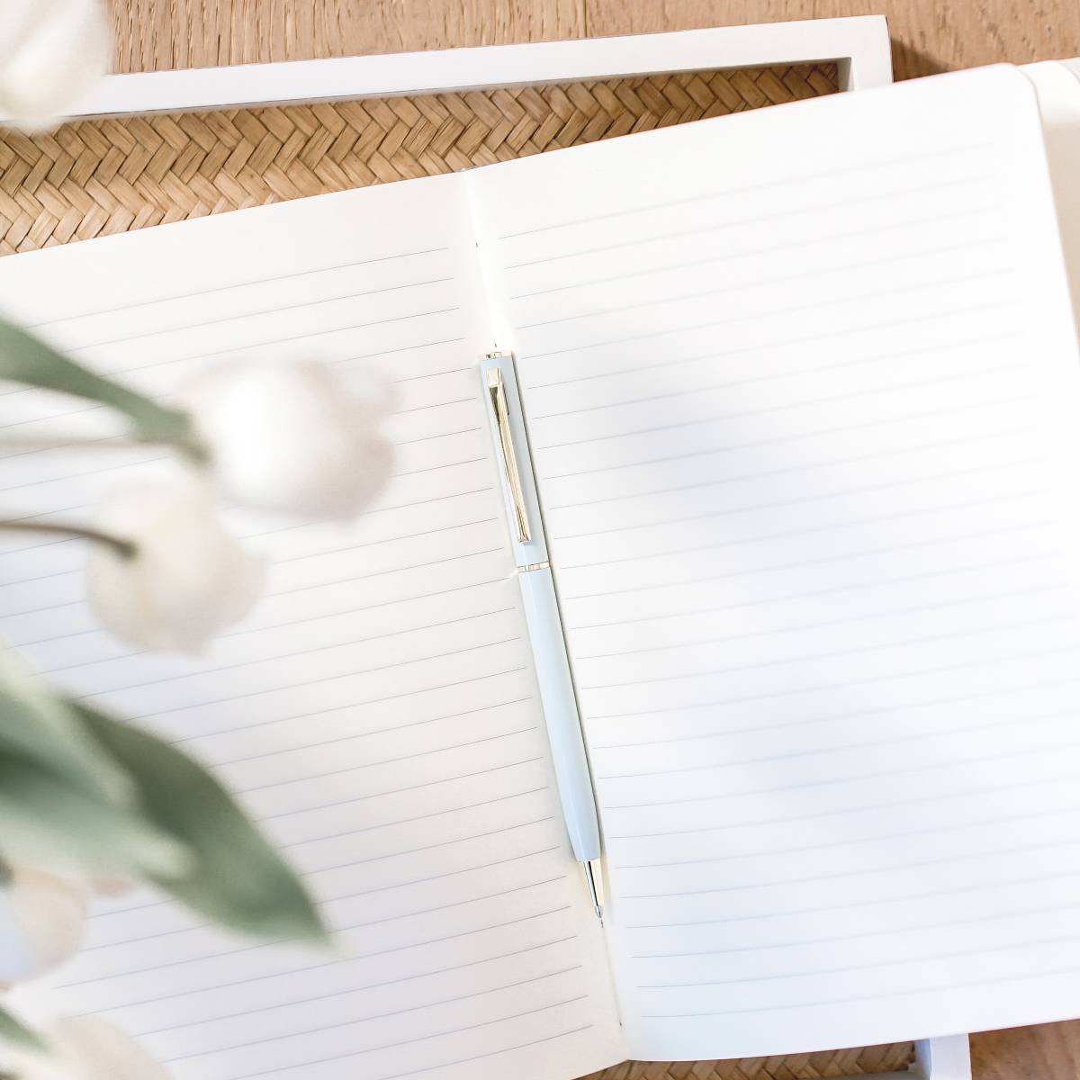 a blank notebook with striped paper and a blue pen