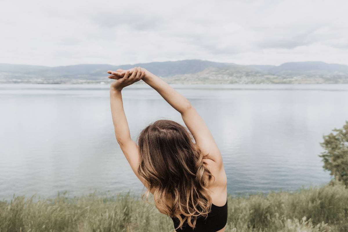 girl stretching by a lake